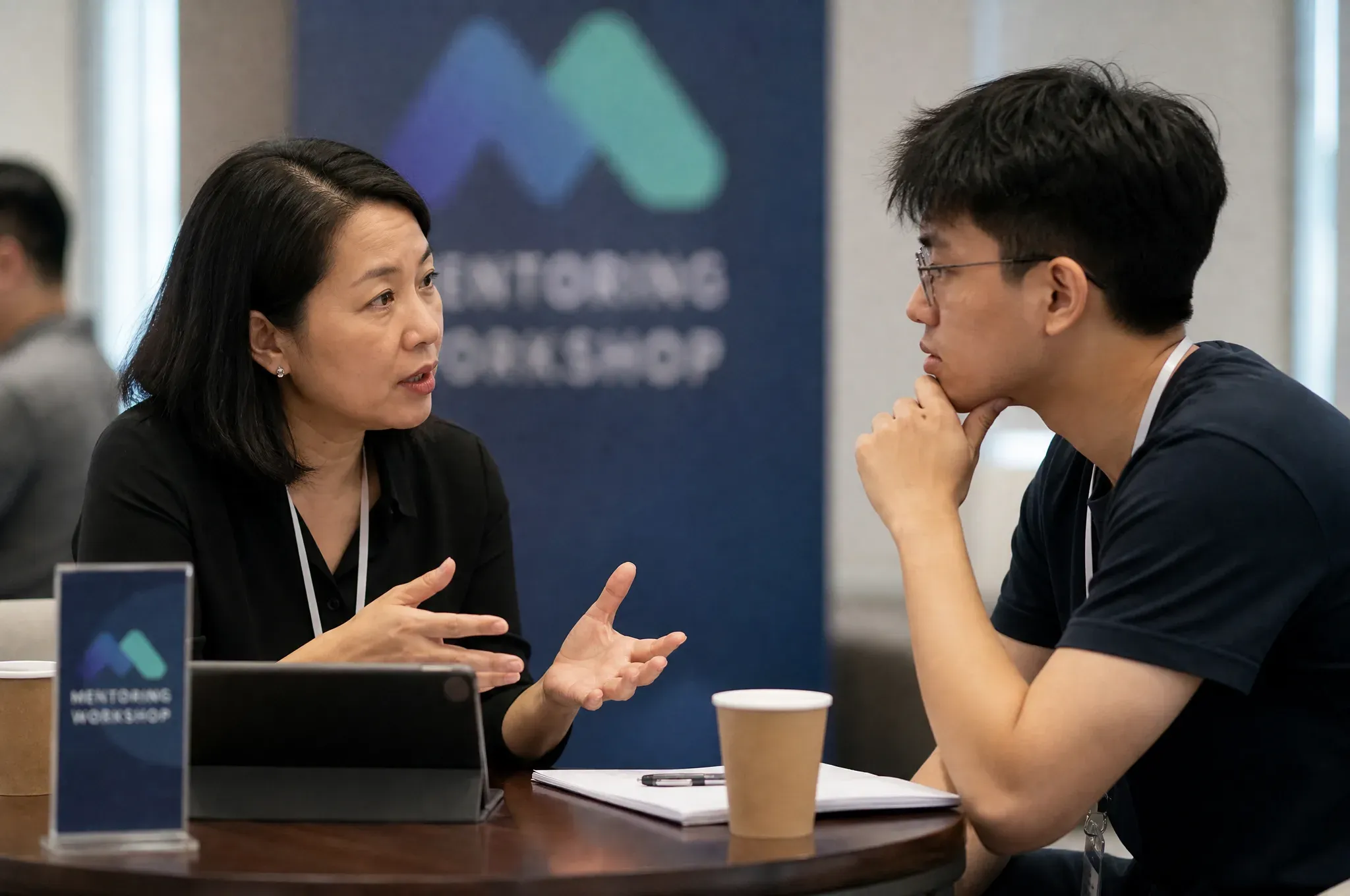 A mentor talking a founder through a problem at a workshop table