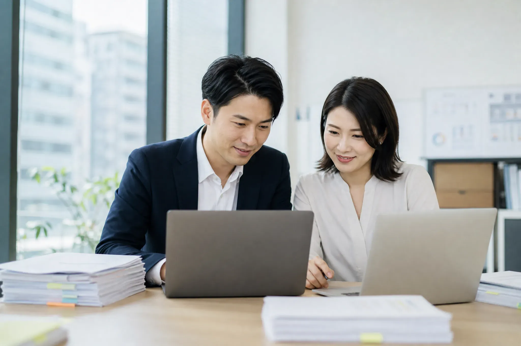 Two corporate services advisors reviewing incorporation filings together at a shared desk